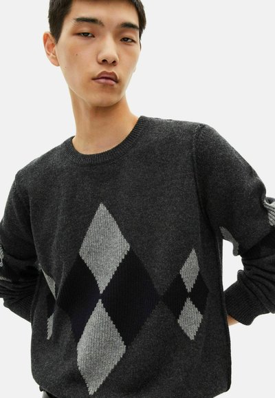 Suéter gris de punto con un patrón de rombos en negro, gris claro y blanco. Cuello redondo y puños acanalados, acabado texturizado.