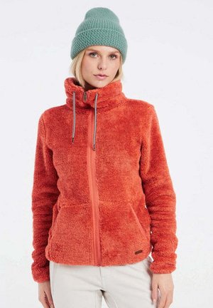 Veste en polaire orange avec un col montant, fermeture éclair à l'avant et deux poches latérales. Équipée d'un cordon de serrage pour un ajustement réglable.