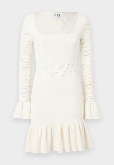 Balta adīta kleita ar kvadrātveida kakla izgriezumu, pilna garuma piedurknēm, kas rotātas ar teksturētu rakstu, un pešā ar volānu apakšējo daļu.