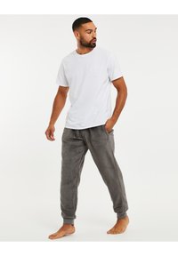 T-shirt en coton blanc à manches courtes associé à un pantalon de jogging en polaire gris avec cordon de serrage et poignets côtelés.