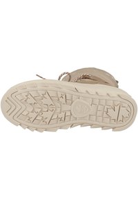 Suela de bota de invierno beige con surcos profundos y patrones de hojas. Presenta cordones trenzados y un logo en el centro. Material de goma texturizado y duradero.