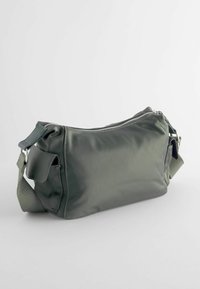 Petit sac bandoulière gris avec une fermeture éclair sur le dessus, une poche avant à rabat et une bandoulière en tissu réglable.