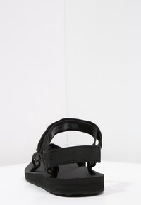 Sandali neri con suola in gomma testurizzata, dotati di due cinturini in tessuto regolabili e un plantare imbottito per il comfort.