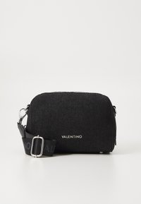 Sac bandoulière noir en tissu avec fermeture éclair, doté d'une sangle imprimée du logo et d'accents en métal argenté. Texture lisse et forme arrondie.