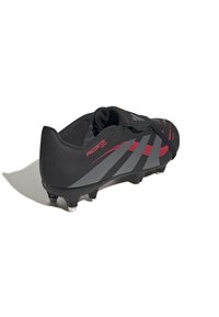Schwarzer Fußballschuh mit strukturiertem Obermaterial, grauen diagonalen Streifen, roten Akzenten und geformten Stollen für Grip. Flexibles Design mit einem engen Sitz.