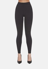 Czarne legginsy z wysokim stanem, wykonane z elastycznego materiału, z pionowymi szwami i płaskim, dopasowanym krojem.