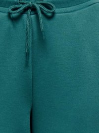 Tealovo zafarbené tepláky s textilnou šnúrkou zviazanou na mašľu na elastickom páse.