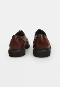 Chaussures en cuir marron avec une finition lisse, bout rond et semelles noires en caoutchouc basses. Présentent des coutures subtiles le long des coutures.