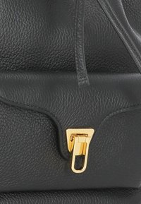 Borsa a mano in pelle nera con superficie strutturata, design rigido e chiusura magnetica in tono oro.