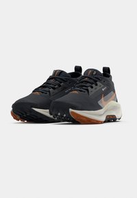 Schwarze Trailrunning-Schuhe mit orangefarbenen Akzenten, strukturiertem Mesh-Obermaterial, strapazierfähiger Gummisohle und verstärkter Fersenlasche für Stabilität.