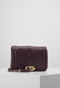 Borsa a tracolla in pelle viola con motivo a zigzag, hardware dorato e tracolla removibile. Forma rettangolare compatta, cuciture dettagliate.
