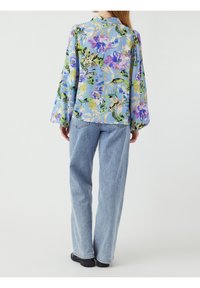 Kwiatowa bluzka w kolorze niebieskim, z długimi, bufiastymi rękawami i luźnym krojem. Połączona z jasnoniebieskimi dżinsami o wysokim stanie.