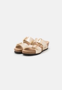 Sandali beige chiari con due ampie cinghie e fibbie circolari dorate. Sottopiede in sughero su una leggera piattaforma con suola in gomma nera.