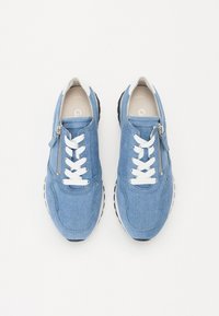 Baskets en denim bleu avec des lacets blancs et une fermeture éclair latérale, dotées d'une semelle rembourrée et d'une semelle extérieure en caoutchouc noir pour une meilleure adhérence.