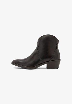 Bota de cuero negro hasta el tobillo con un borde curvado, tacón bajo y detalles de costura sutiles a los lados. Textura suave y puntera redondeada.