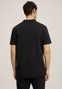 Czarna koszulka polo widziana z tyłu, z klasycznym kołnierzykiem i krótkimi rękawami, wykonana z gładkiej bawełny, z prostym dołem.