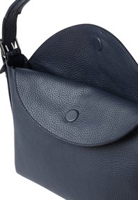 Sötétkék, szemcsés textúrájú bőr kézitáska, lekerekített fedéllel és biztonságos patenttal záródik. Állítható pánttal rendelkezik.