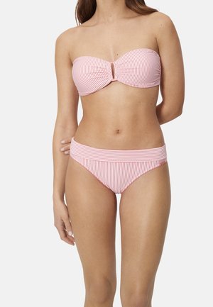 Mujer con bikini de tipo bandeau a rayas rosas y blancas, combinado con parte inferior a juego, sobre un fondo claro y liso.