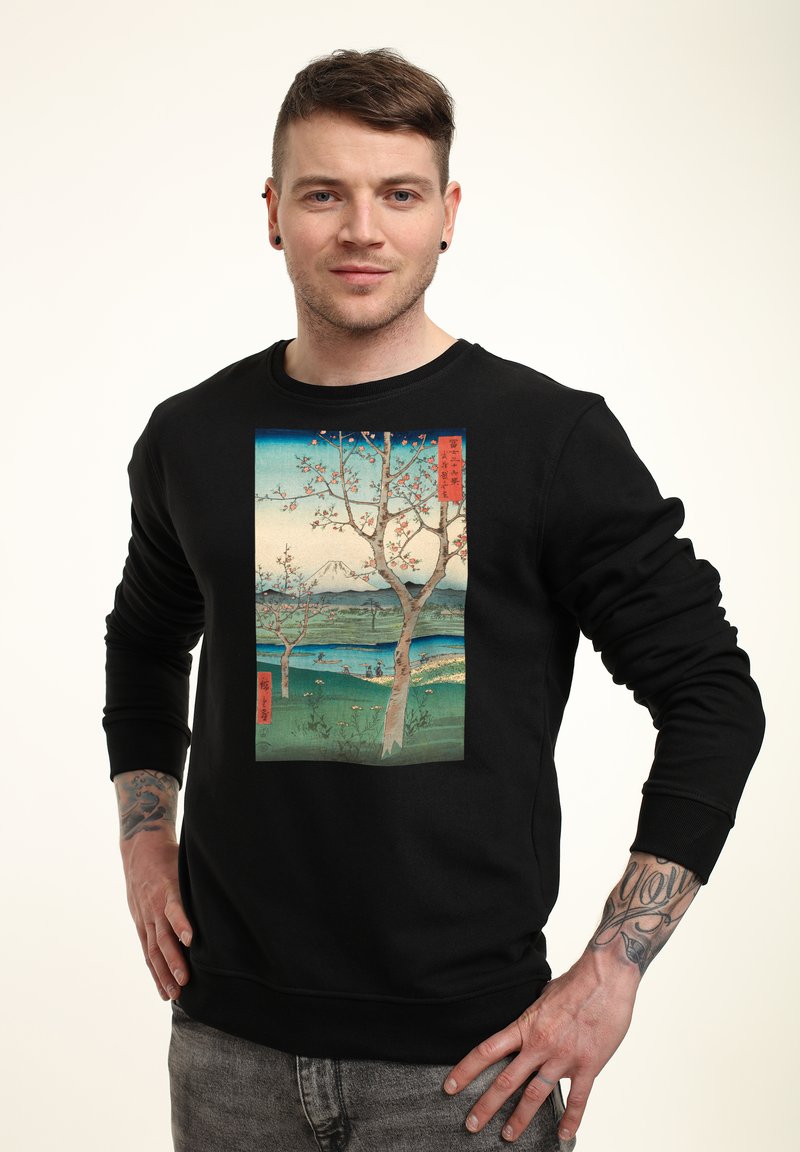 Felpa nera con una grafica frontale di un dipinto paesaggistico con alberi, acqua e una montagna, impreziosita da testo giapponese rosso.
