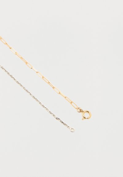 Αλυσίδες από χρυσό και ασήμι πλεγμένες μεταξύ τους· ο χρυσός έχει επιμηκυμένους συνδέσμους και στρογγυλό κούμπωμα, ενώ το ασήμι διαθέτει στριφτό σχέδιο και λιτή διακόσμηση.