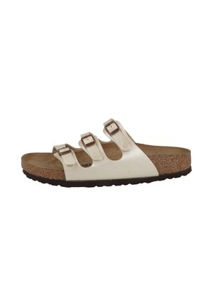 White slide sandal with three adjustable buckled straps, cork footbed, and textured black sole, side view.