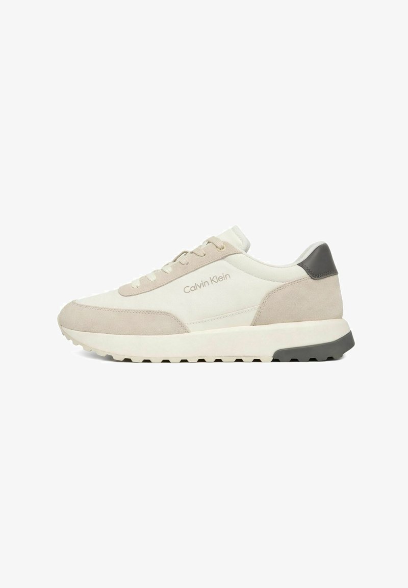 Flacher beige-cremefarbener Calvin Klein Sneaker mit Wildlederpanels, Schnürdesign und schwarzem Fersenakzent auf weißer Sohle mit profiliertem Außensohle.