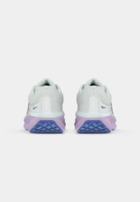 Deux baskets avec une tige en maille grise douce, une semelle intermédiaire blanche et lavande, et une semelle extérieure texturée bleue. Accents réfléchissants sur le talon.