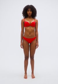 Σετ κόκκινου μπικίνι με επενδυμένο τοπ σουτιέν με λεπτές τιράντες και συνοδευτικό κανονικό σλιπ με χαμηλή μέση, ομαλή υφή, χωρίς ορατά σχέδια ή διακοσμητικά.