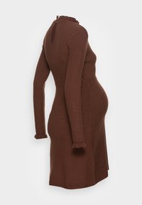 Brunstickad klänning med långa ärmar, volangkrage och manchetter, sidoklyfta och åtsittande midja, designad för att passa en gravid siluett.