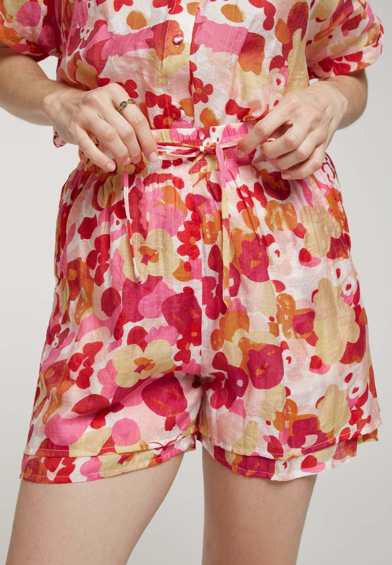 Shorts légers à motifs floraux dans des teintes rose, rouge et orange, dotés d'une taille élastique avec un lien et de poches latérales.