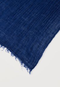 Μπλε ελαφρύ ύφασμα με ελαφρώς ζαρωτή υφή και ξεφτισμένες άκρες σε λευκό φόντο.