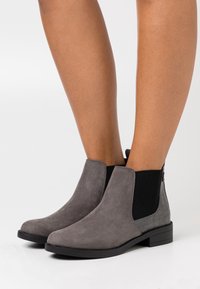 Grijze suède enkellaarsjes met een gladde afwerking, elastische zijkanten en een getextureerde krokodillenpatroon accent op de hak. Blokhak ontwerp.