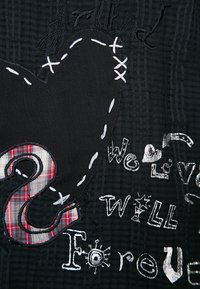 Tissu noir avec des patchs brodés, présentant une forme de cœur, un motif à carreaux et des textes : « ami », « Nous aimons » et « SERA toujours ». 