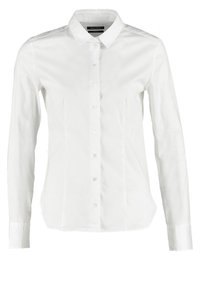 Camicia bianca a maniche lunghe con colletto a punta, realizzata in tessuto liscio, con un design aderente e sette bottoni frontalmente.