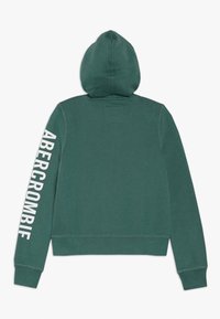 Haut à capuche en coton vert avec un design ajusté. Il dispose d'une capuche, de manches longues et de "ABERCROMBIE" imprimé verticalement sur la manche gauche.