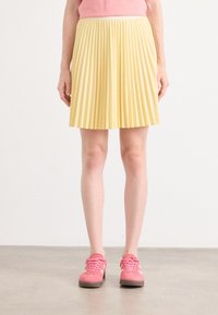 Gonna gialla plissettata con vita alta, di lunghezza al ginocchio, realizzata in un tessuto leggero; texture liscia con un motivo uniforme su tutta la superficie.