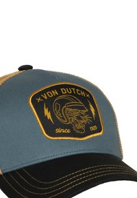 Gorra de camionero con la parte frontal de algodón azul y negro, trasera de malla dorada, y un parche bordado negro con un tigre y un logo.