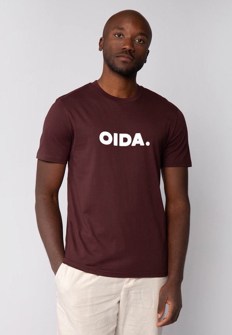 Bordeauxfarbene Baumwoll-T-Shirt mit kurzen Ärmeln und rundem Halsausschnitt. Mit großen weißen Buchstaben "OIDA." auf der Brust. Schlichtes Design mit minimalen Details.