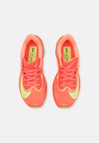 Neon-pinke Laufschuhe mit gelben Akzenten, Obermaterial aus Mesh, gepolstertem Kragen, flachen Schnürsenkeln und einer strukturierten Außensohle für Grip.