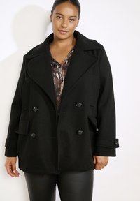 Schwarzer zweireihiger Wollmischmantel mit großen Revers, übergroßen Taschen und Knopfakzenten. Strukturierter Stoff mit weiter Passform.