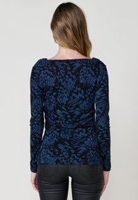 Top de manga larga en azul marino con un patrón floral en un tono azul más oscuro, con escote redondeado y diseño ajustado.