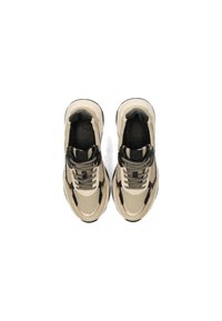 Scarpe sportive beige e nere con tomaia in rete, dettagli testurizzati e lacci neri; suola rialzata con battistrada a motivo.