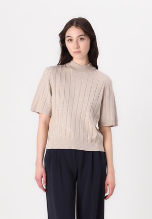Beige geribbelde gebreide top met korte mouwen en een hoge halslijn, met een licht schitterende textuur, gecombineerd met donkere op maat gemaakte broeken.
