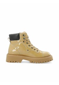 Bottine en cuir verni jaune avec un talon noir, des œillets en métal et une semelle en caoutchouc épaisse dotée de profondes rainures pour une meilleure adhérence.