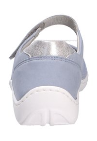 Sandale bleu clair ornée d'un accent métallique argenté au talon, présentant une texture douce et une semelle blanche contrastante.