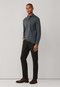 Polo de manga larga color carbón, mezcla de algodón, con cuello clásico. Combinado con pantalones verde oscuro y zapatos marrones de cordones. Diseño simple.