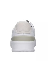 Sneaker bianco con una tomaia liscia e testurizzata e un accento in suede grigio sul tallone. Caratterizzato da una suola spessa bianca con una striscia verde tenue.