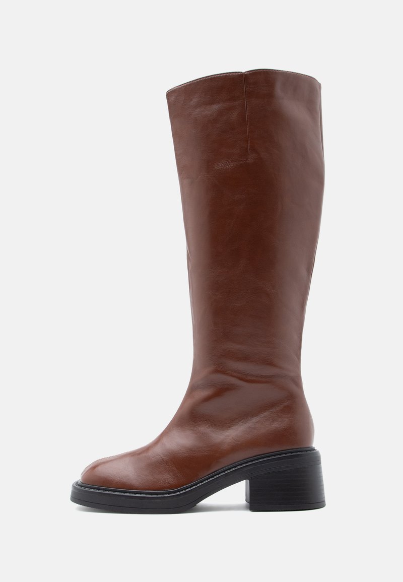 Καφέ δερμάτινες μπότες μέχρι το γόνατο με στρογγυλεμένη μύτη και χοντρό μαύρο τακούνι. Λείο υφή με ελάχιστες ραφές.