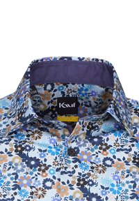 Camicia a maniche lunghe con motivo floreale, caratterizzata da una combinazione di colori blu, crema e marrone; colletto aperto; tessuto morbido; etichetta con il marchio visibile.