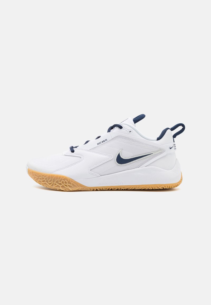Witte sportschoen met een getextureerde gumzool, voorzien van marineblauwe accenten, een gladde bovenkant en een kenmerkend Nike swoosh-logo.